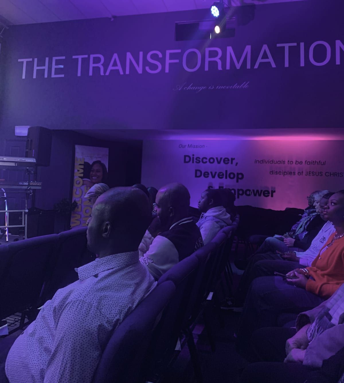 Our room during a gathering: the congregation seated in rows beneath the words The Transformation Edge, A change is inevitable, and our mission painted on the wall.