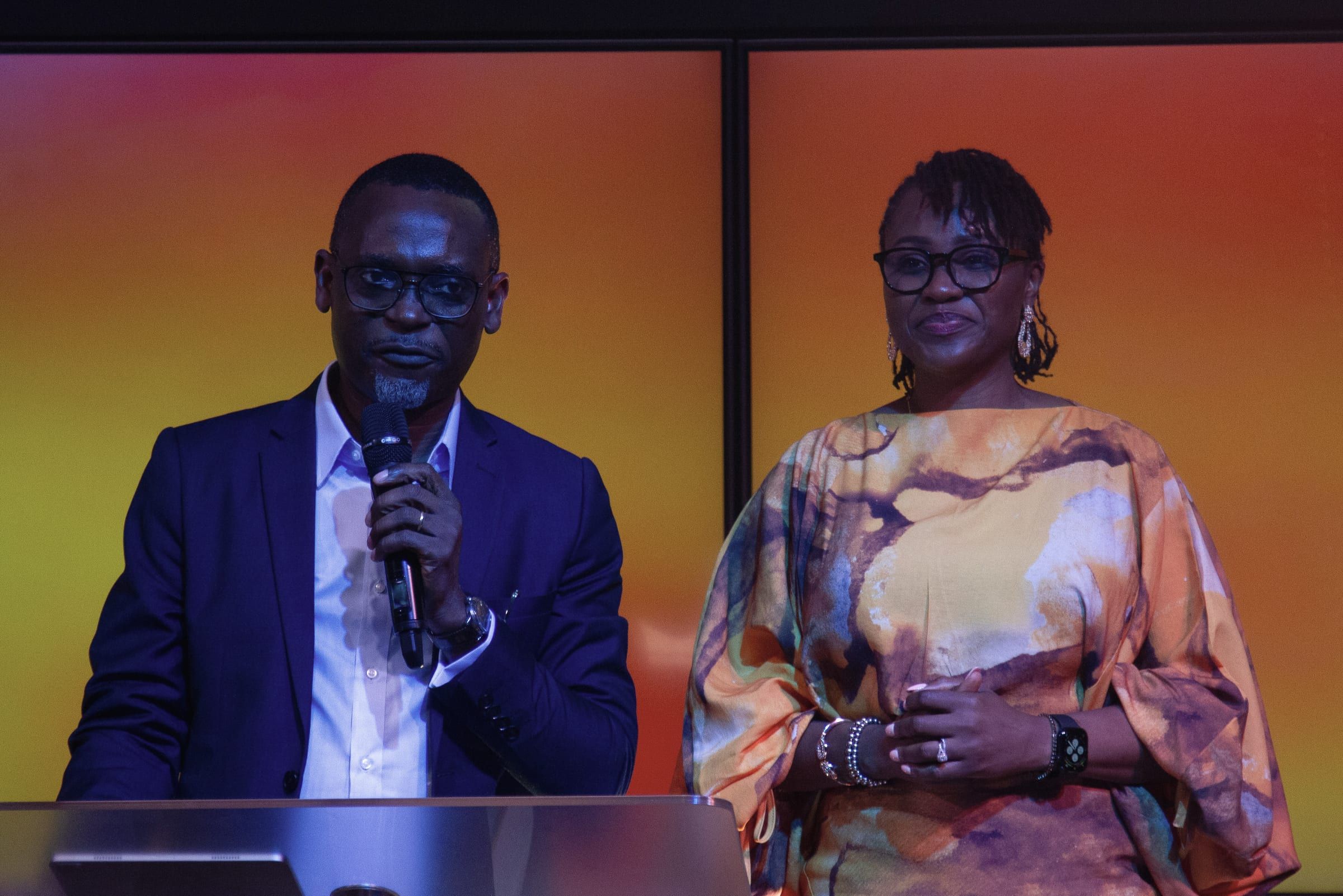 The Senior Pastors, Dr Michaels Aibangbee and Pastor Osas Aibangbee, standing together at the lectern during a gathering.