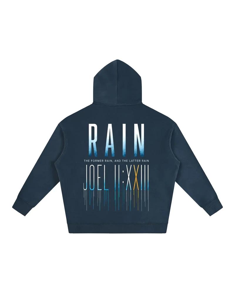 A mockup of the RAIN fleece hoodie in navy, from the back: RAIN in tall letters shading from white to blue, the words “The former rain, and the latter rain”, and Joel 2:23 in Roman numerals beneath, its strokes running down like rain.