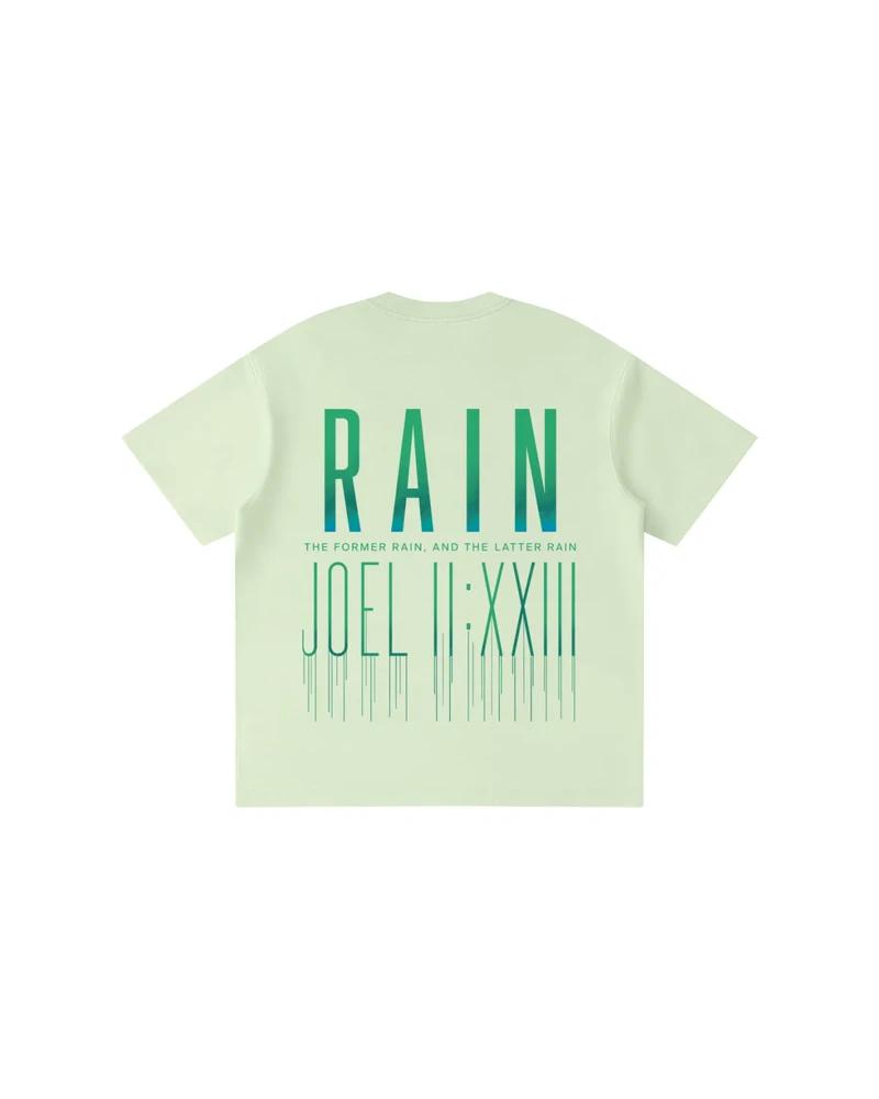A mockup of the RAIN kids' t-shirt in green, from the back: RAIN in tall letters shading from green to white, the words “The former rain, and the latter rain”, and Joel 2:23 in Roman numerals beneath, its strokes running down like rain.