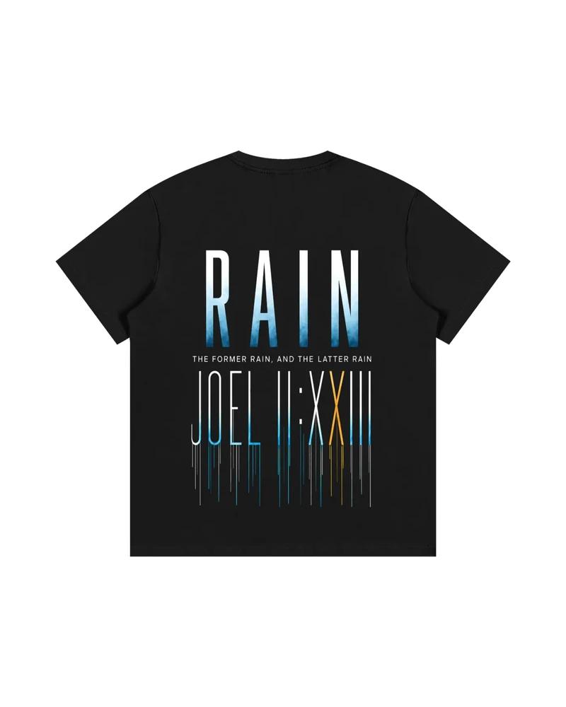 A mockup of the RAIN oversized t-shirt in black, from the back: RAIN in tall letters shading from white to blue, the words “The former rain, and the latter rain”, and Joel 2:23 in Roman numerals beneath, its strokes running down like rain.