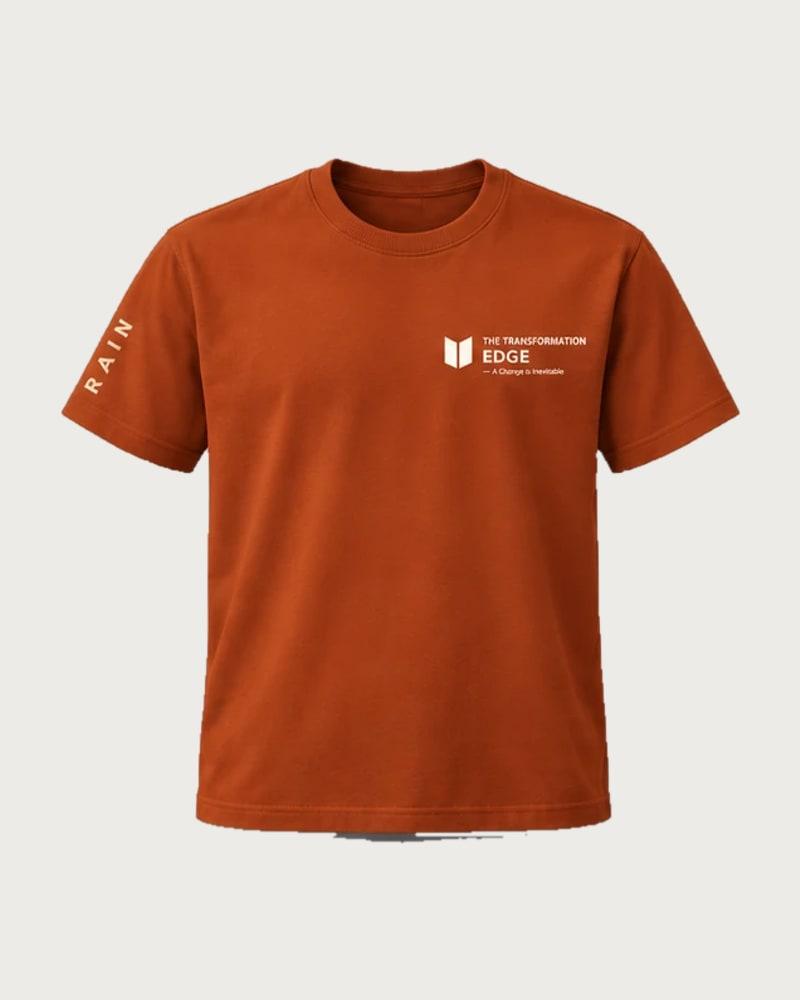 A mockup of the RAIN t-shirt in rust, from the front: The Transformation Edge mark on the chest and RAIN down one sleeve.